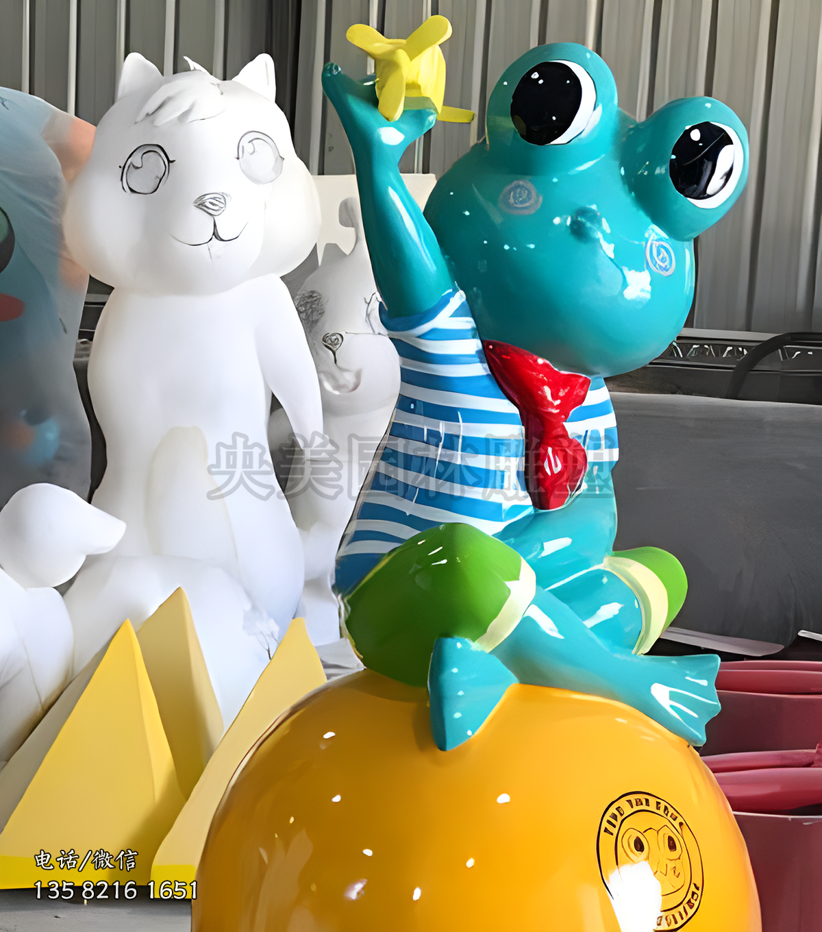 坐在球上放飛機的卡通青蛙雕塑